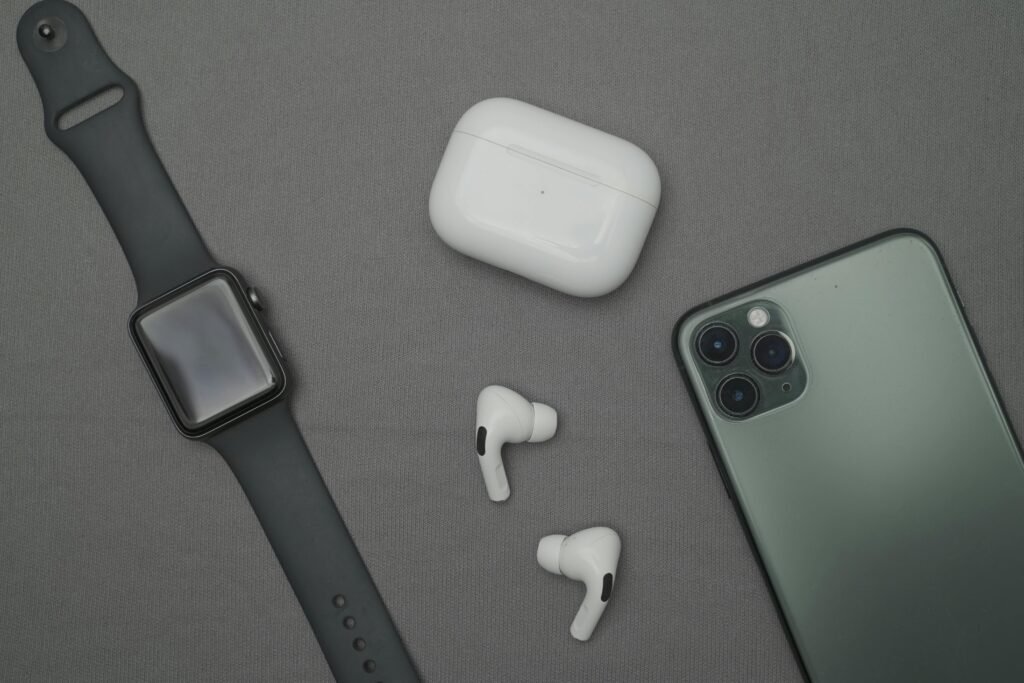 Flat lay of smartwatch, smartphone, and wireless earbuds on a gray background.